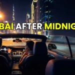 A couple driving a convertible luxury car through the illuminated Sheikh Zayed Road tunnel at night in Dubai.