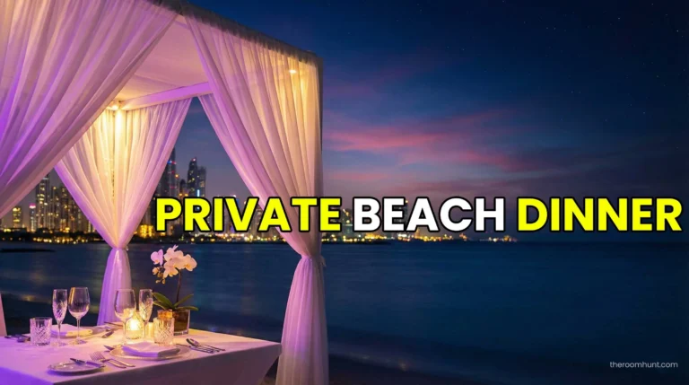 A romantic private beach dinner setup with white drapes and candles at sunset in Dubai with the Burj Al Arab in the distance.