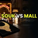 A stylish woman examining a gold necklace in the Dubai Gold Souk with a reflection of modern jewelry boutiques in the background.